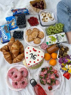 a table topped with lots of different types of cakes and pastries on top of a bed