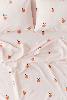 an unmade bed with white sheets and oranges on it's coverlet