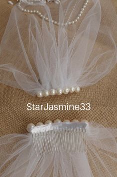 two hair combs with pearls and tulle attached to each other on a piece of cloth