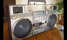 an old fashioned boombox sitting on top of a wooden table next to a potted plant