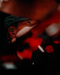 a man with ear piercings looking at something in the distance while wearing a hat