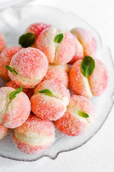 powdered sugar covered donuts on a plate with mint sprigs and leaves