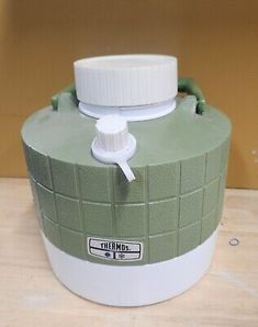 a green and white water bottle sitting on top of a wooden table next to a wall