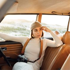 a woman sitting in the back seat of a car with her hand on her head