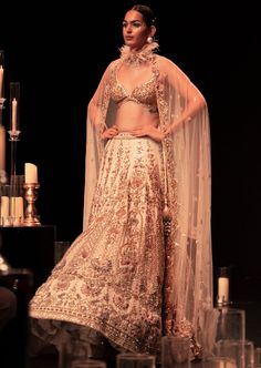 This enchanting earthy beige lehenga set is a beautiful blend of exuberance and grandeur. An ensemble that you will want this wedding season includes a lehenga, a blouse, a dupatta and a veil. Stitched to perfection, the lehenga features 3D embroideries with organza flowers using pearls, salli, cutdana, and stud tassels. The sleeveless blouse features a scintillating sweetheart neckline with handcrafted finish and a back hook closure. Paired with a heavy net dupatta, the cut-work detailing and intricate embroidery take center-stage. The lehenga comes with an attached cancan and the blouse has padding. Completed with a veil, this opulent ensemble silhouette will glimmer in the spotlight. Dry-clean only if required. Slight variation in color is possible due to digital photography. Beige Lehenga, Organza Flowers, 3d Embroidery, Net Dupatta, Intricate Embroidery, Bridal Lehenga, Cut Work, Center Stage, Digital Photography