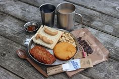 a metal plate topped with lots of food next to two mugs filled with coffee