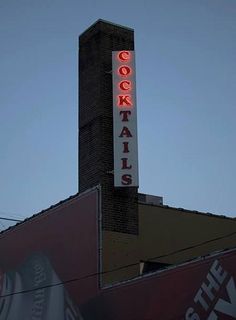 a tall brick building with a neon sign on it's side that reads cocktails