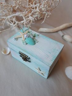 a wooden box with seashells and starfish on it sitting on a table