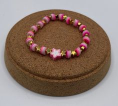 Pink Star Bead Bracelet by AHW This bracelet has been handmadewith care and has two tone pink beads with gold stars Pink Star-shaped Beaded Bracelets, Adjustable Pink Star Bracelets, Adjustable Pink Beaded Bracelet With Star Charm, Adjustable Pink Beaded Bracelets With Star Charm, Pink Beaded Bracelets With Star Charm, Pink Star-shaped Jewelry With Colorful Beads, Star Bead Bracelet, Pink Star, Pink Stars