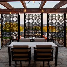 an outdoor dining area with chairs and table in front of a screen wall that overlooks the city