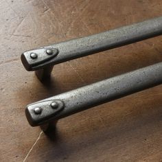 two metal handles sitting on top of a wooden table