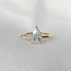 an engagement ring with three stones on top and one stone in the middle, sitting on a white surface