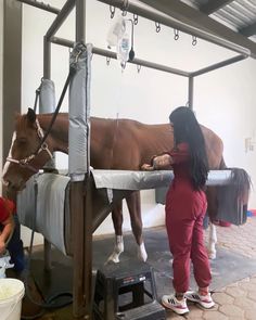 a woman standing next to a brown horse on top of a white bed covered in blankets