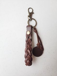 a brown leather keychain hanging from a metal hook on a white table top