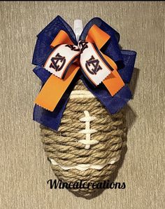 an orange and blue football tied to a rope with a bow on top that says, wincrafts