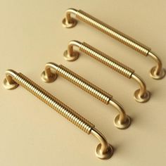 four brass colored screws are lined up in a row on a beige surface,