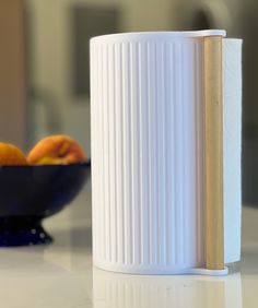 a white vase sitting on top of a table next to oranges and a bowl