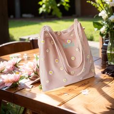 a pink purse sitting on top of a wooden table next to vases filled with flowers