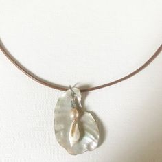 a necklace with a shell and pearl on it