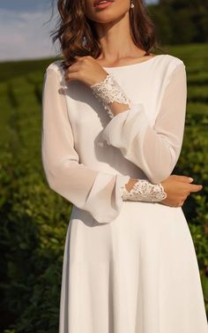 a woman in a white dress is posing for the camera with her hand on her shoulder