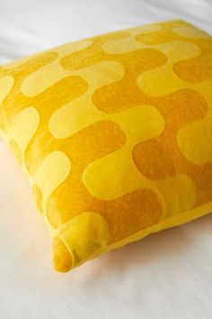 a yellow pillow sitting on top of a white bed