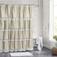 a white shower curtain with ruffles on it in a bathroom next to a toilet