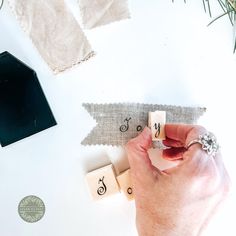 a person's hand is placing letters on top of some fabric and other crafting supplies