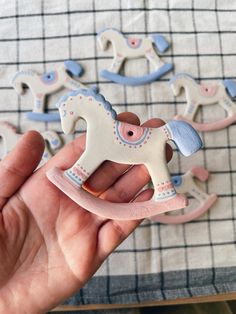 a hand is holding a toy horse in front of some other toys on a table