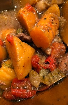 a stew with potatoes, carrots and other vegetables in a brown bowl on a table