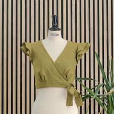 Wrap crop moss green top, short, sleeveless and with two ruffles on the shoulder, it has five pleats under the chest. It closes with a bow that goes around the waist and ties on the left side that we can adjust more or less. Ideal for events, it is a versatile top that we can combine in different looks and styles. Made of premium quality linen, it is a natural, fresh and breathable fabric. Spring Ruffled Short Sleeve Crop Top, Short Sleeve Ruffled Crop Top For Day Out, Elegant Ruffled Summer Crop Top, Elegant Fitted Cotton Crop Top, Summer Wrap Crop Top, Green Non-stretch Summer Top, Chic Green Wrap Top, Trendy Ruffled Short Sleeve Crop Top, Elegant Cropped Summer Blouse