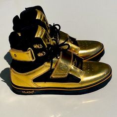 Vlado Royal Metallic Gold & Black Hi Top Sneakers Size 7 Mens = 8.5 Women Feature Plush Black Outside Padding With Gold Lion Hardware On Cross Strap. Gold Accents And Tongue With The Royal Crest And Vlado Lion Symbol. Vlado On Outer Mid Sole And Gum Bottoms. Gold Laces Included. Doesn’t Get Any Better Than This! For The Royal Ones Only! Lion Symbol, Royal Crest, Hi Top Sneakers, Gold Lion, Gold Lace, Hi Top, Cross Straps, Mens Shoes Sneakers, Metallic Gold