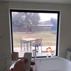 a person holding a remote control in front of a bathtub with a table and chairs