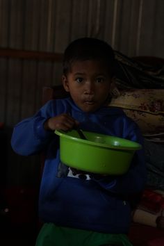 a young boy holding a green bowl in his hands