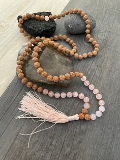 A most have addition to your Mala Necklace collection. A knotted mala with a mix of rose quartz beads and Rudraksha beads with a light pink tassel at the bottom. A stylish necklace that will also keep you grounded. Use it as a necklace, as a bracelet, even as a decor item in your room, or praying/ meditating area. The mala is 47cm- 18.5 inch drop length (without the tassel) The bottom tassel is 7.5cm- 3 inch long. The perfect gift for your loved ones. ⚡️Join Akashi's VIP list for early bird disc Spiritual Hand Knotted Mala As Gift, Adjustable Rose Quartz Beaded Necklace For Healing, Pink Round Beads Necklaces For Meditation, Pink Round Beads Necklace For Meditation, Bohemian Rose Quartz Crystal Necklace With Round Beads, Spiritual Rose Quartz Beaded Necklaces For Healing, Rose Quartz 108 Beads Jewelry For Meditation, Adjustable Bohemian Rose Quartz Beaded Necklace, Adjustable Spiritual Rose Quartz Beaded Necklaces