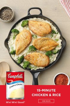 chicken and rice cooking in a skillet with ingredients on the table next to it