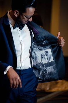 a man in a tuxedo holds up his jacket to show off some photos