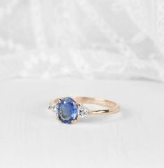 an oval shaped blue sapphire and diamond ring on a white background with the top half of it