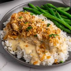 a plate filled with rice, green beans and meat covered in gravy on top of it