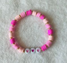 Heishi/clay beaded bracelet: Pink hearts  -good quality -very stretchy -one size: about 6.5 inches (can stretch to around 8 inches)  This bracelet contains various shades of pink heishi/clay beads, gold sead beads, and two shades of pink heart beads upon very stretchy string.  This bracelet comes in one size (measures about 6.5 inches) and is meant to fit people with small and medium size wrists. If you have a larger wrist than about 8 inches, then send me a message to get a custom bracelet. Handmade Pink Heishi Beads Stretch Bracelet, Trendy Pink Heishi Beads Stretch Bracelet, Trendy Pink Heishi Beads Friendship Bracelet, Pink Heishi Beaded Bracelets With Letter Beads, Pink Heishi Beads Bracelets, Pink Heishi Beads Bracelet With Letter Beads, Pink Heishi Beads Stretch Bracelet For Friendship, Trendy Pink Heishi Beads Bracelet, Pink Heishi Beads Bracelets For Friendship