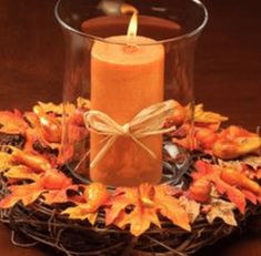 a lit candle sitting on top of a basket filled with leaves