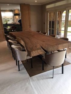 a large wooden table surrounded by chairs in a room with doors leading to the outside