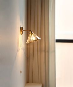 a light that is on in the corner of a room next to a curtained window