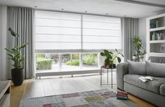 a living room filled with furniture and windows covered in shades of grey drapes next to a wooden floor