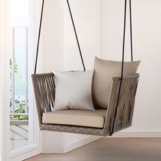 a hanging chair with two pillows on the back and one pillow on the front, in an empty room