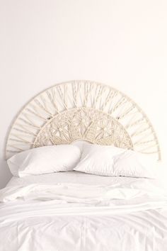 a bed with white linens and pillows on it's headboard in a bedroom