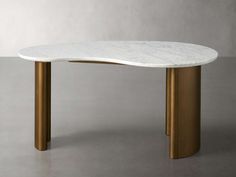 a white marble table with gold legs on a grey surface, in front of a gray wall