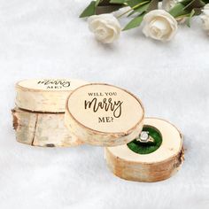 two wooden slices with wedding rings in them on a white blanket next to some flowers