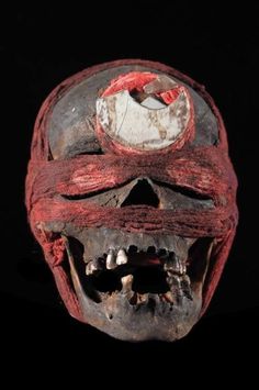 an old skull with red and white decorations on it's head, showing the teeth