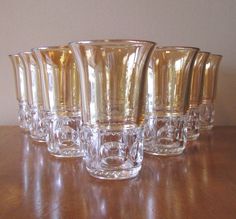 a group of glass cups sitting on top of a wooden table next to each other