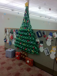 an office cubicle decorated for christmas with a green tree and snowmen on the wall